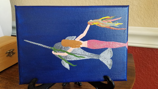 Mermaid decorating a narwhal with ribbons painting 5×7 (comes with stand)
